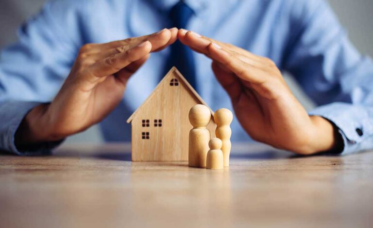 A person reviews a credit report and insurance policy documents at their kitchen table.